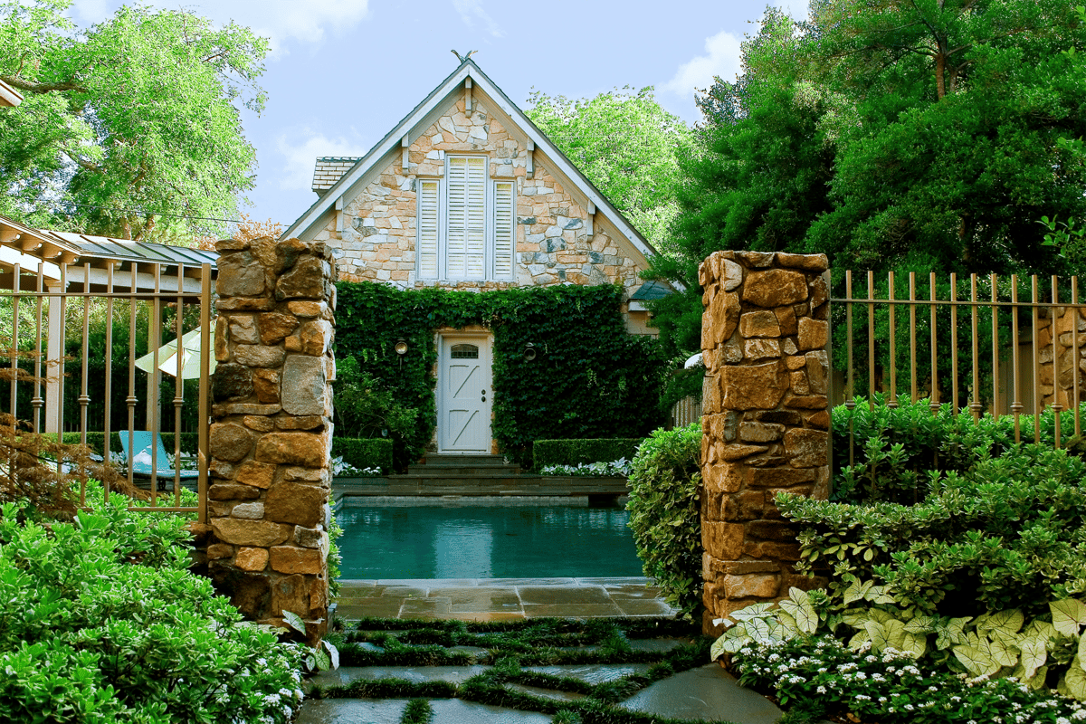 residential stone pillars pool planting beds shade trees