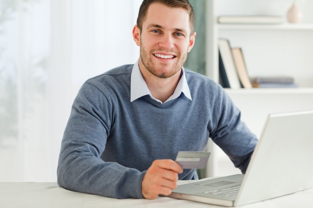 Young male with credit card at his laptop